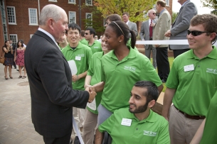 Sonny Perdue, chancellor of the University System of Georgia, shakes hands with a young student in a green T-shirt..