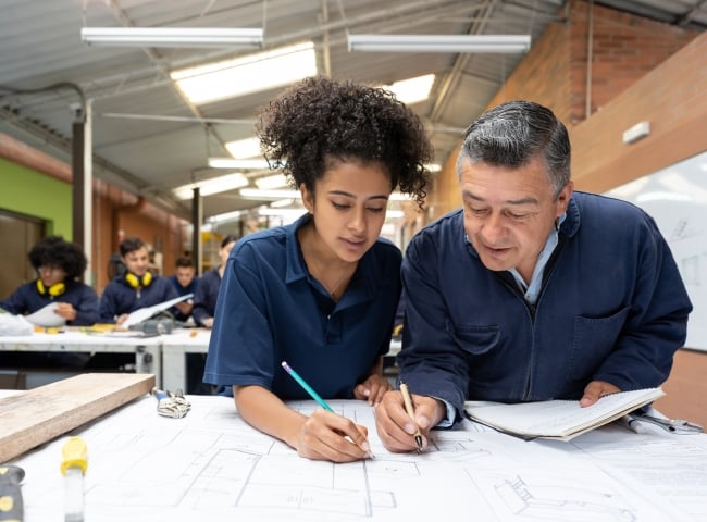 College students working together on a design project and drawing on a blueprint.