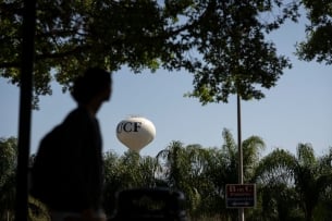 A water tower with the letters "UCF" on it sits in the distance; there is a blurry silhouette of a person in the foreground.