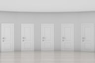 Pale gray hall with five white doors that look exactly the same