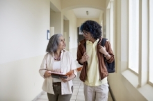 Female professor talks with student in a hallway