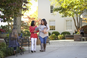 Two students walking and holding books on the campus of Athens State University