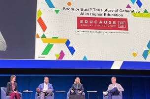 A group of panelists - two women, two men - sit on a stage in a line at a conference. The Educause logo is behind them.