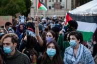 Students, clad in masks, hold up Palestinian flags during a protest on Columbia's campus.