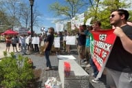 Protesters stand with a sign asking Cornell to remove Starbucks from campus. There is also a man with a bullhorn.