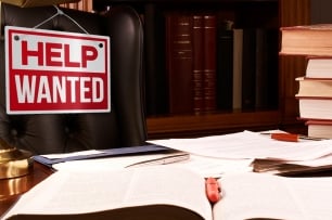 Photo illustration of an empty desk and Help Wanted sign