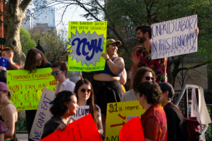 New York social work students hold up signs asking their universities to compensate them for fieldwork.