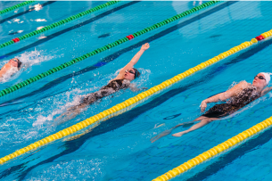 Three female swimmers swim in three different pool lanes.